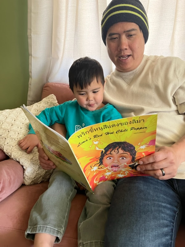 Father and son reading a book from United Way on the couch