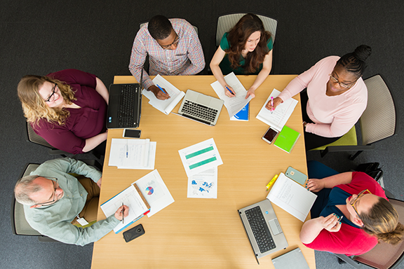 Top down view of multicultural people sitting around a table and strategizing together.