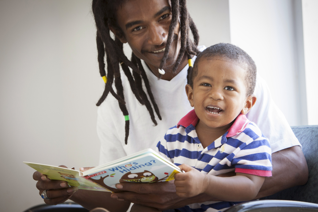 father and young son share a book together. It's so cute.