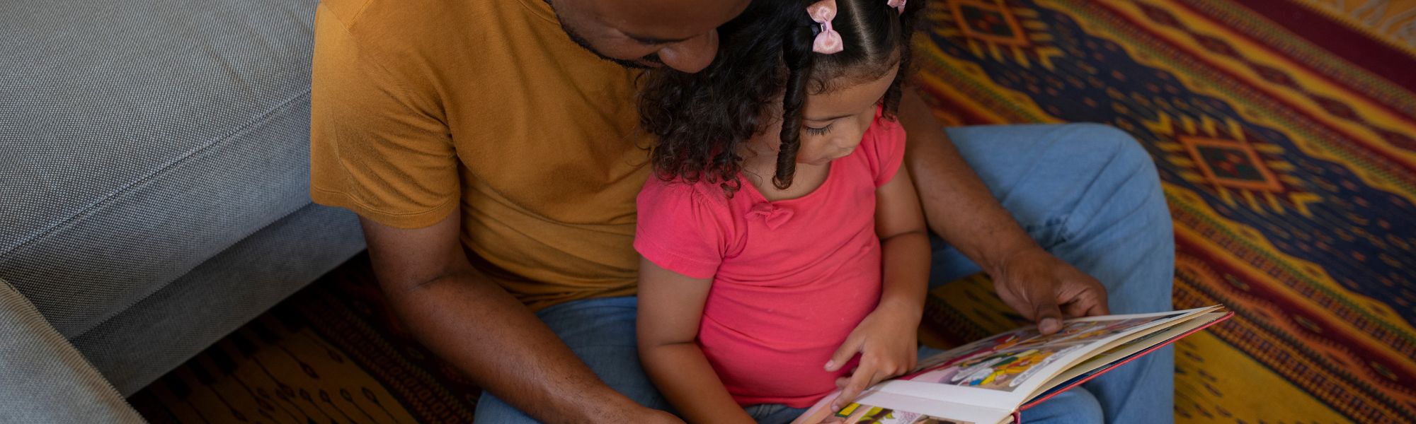 father and daughter reading together on the floor