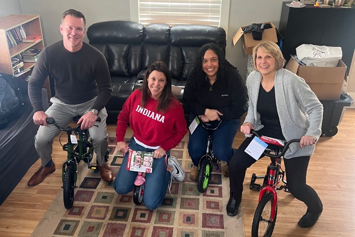 Julie Bosma, Jessica Iasparro, Roger Raley, and Sara Tusler sit on donated children’s bicycles at United Way’s Irving Avenue Strong Neighborhood House during a community donation event in Rockford, Illinois.