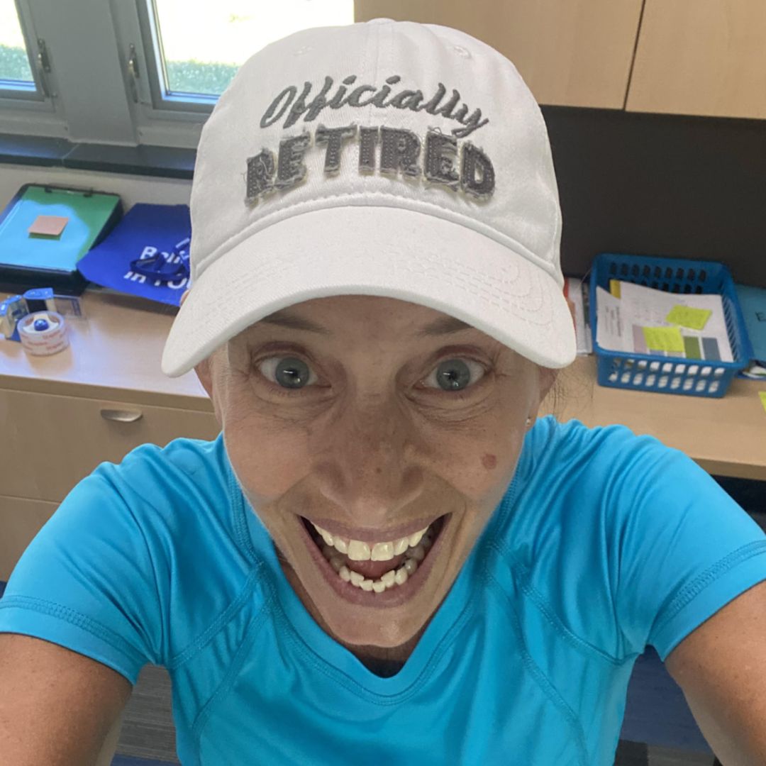 Three young boys smiling and holding books at the Brooke Road Community Center, standing in front of a bookshelf filled with children’s books