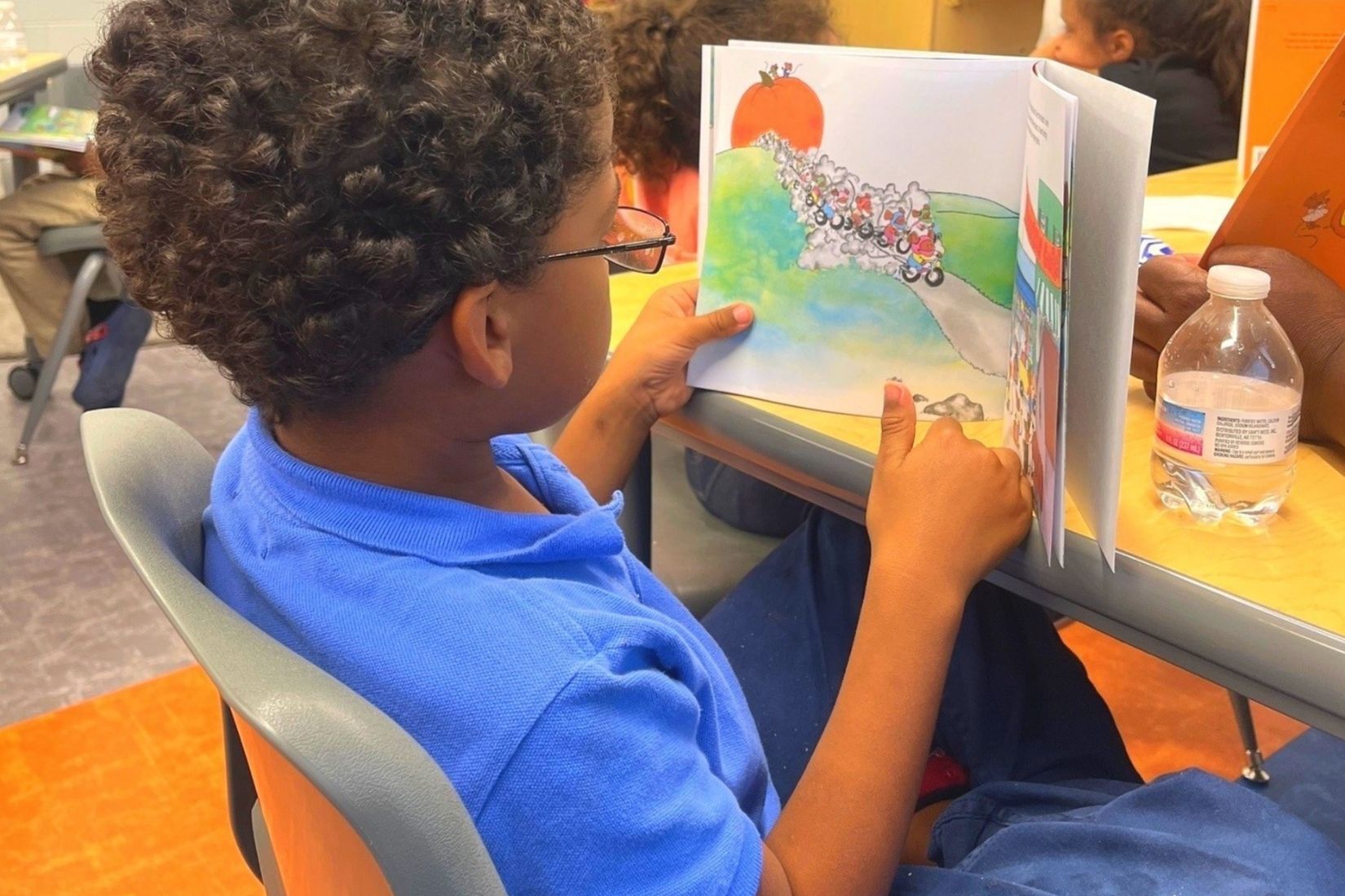 young boy reading a book in a classroom