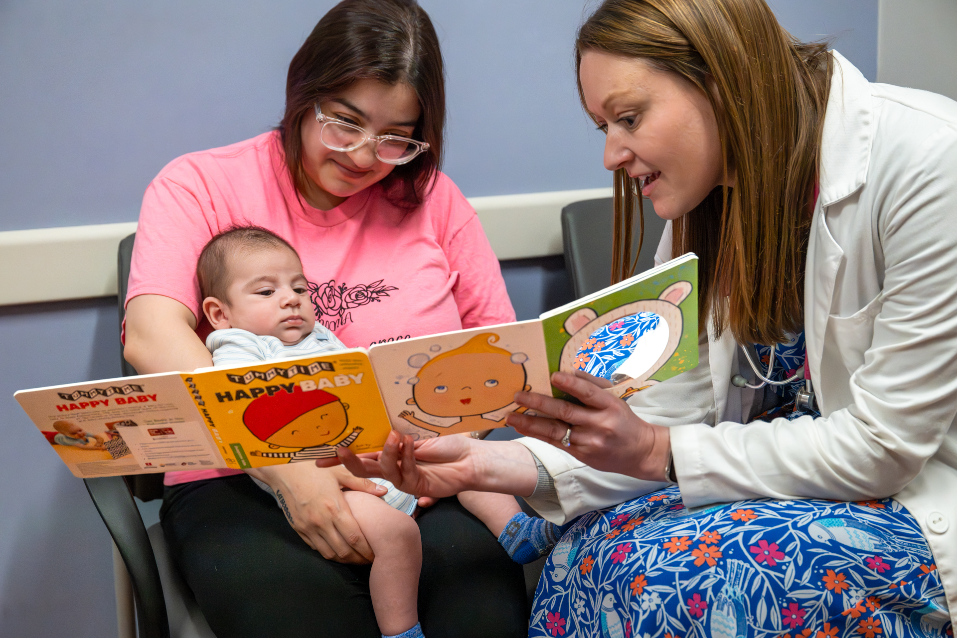 A Crusader Community Health provider shares a board book with a mother and her infant during a well-child visit as part of the Reach Out & Read program.
