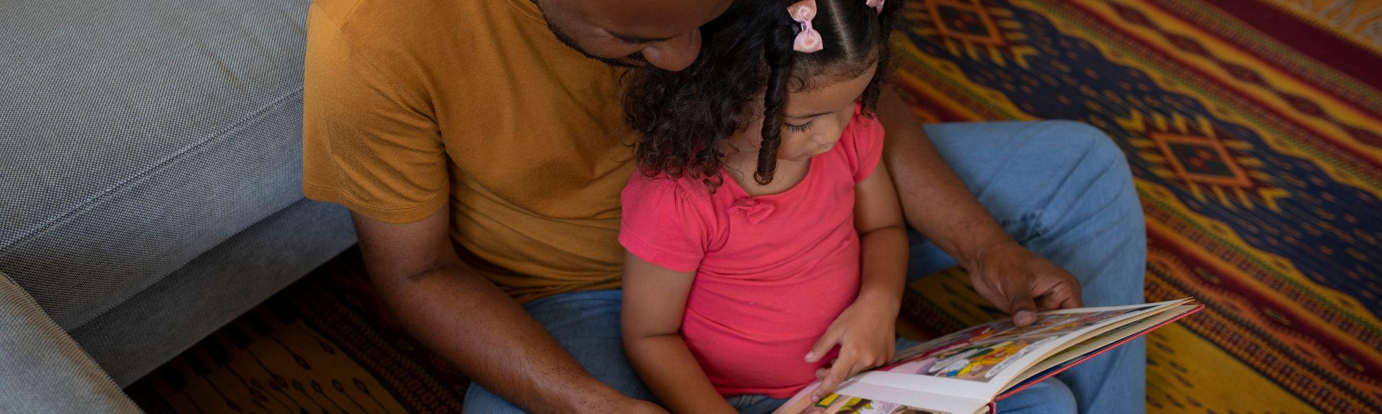 father and daughter reading together on the floor
