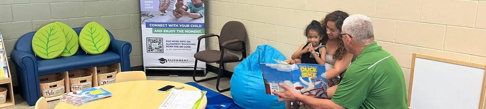 Volunteer Reading a Book to a child and her mother