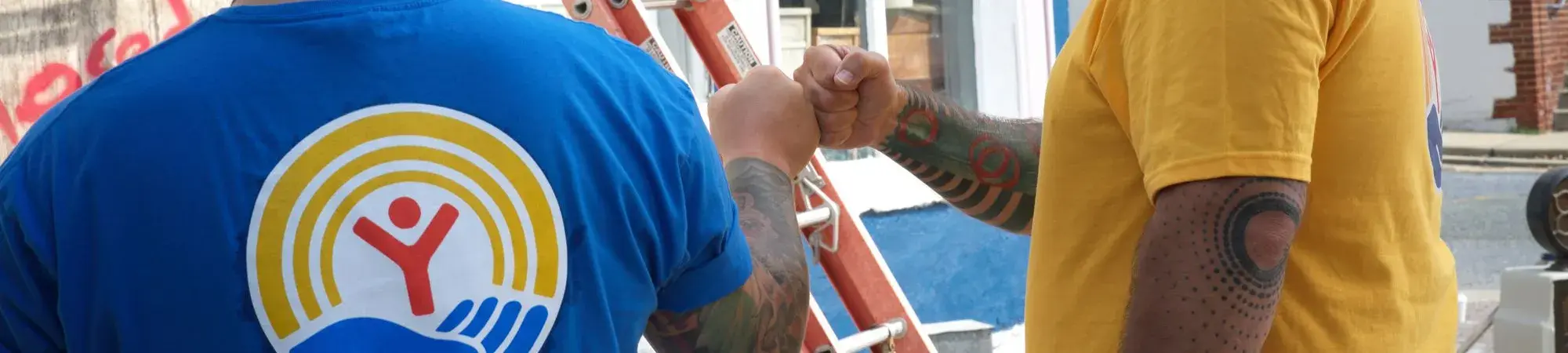 Two guys in United Way t-shirts giving a fist bump