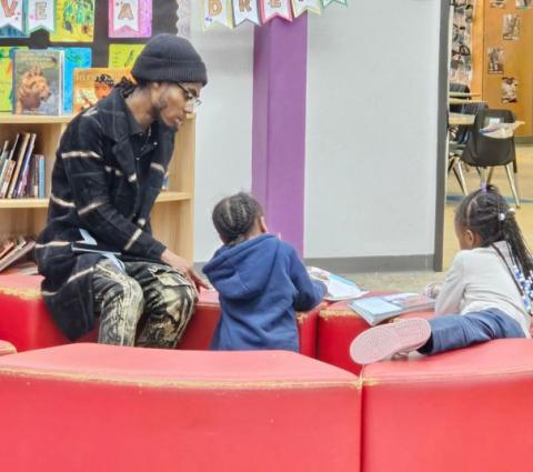 Reading mentor with two young children reading books
