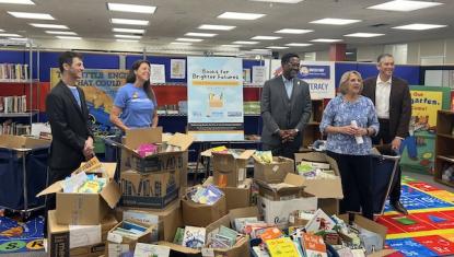 State Representatives Dave Vella and Maurice West join United Way Rock River Valley staff and community partners surrounding dozens of boxes and bins overflowing with donated children's books collected during the Books for Brighter Futures drive.