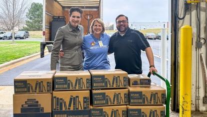 Britten Follett (CEO, Follett Content), Julie Bosma (United Way Rock River Valley), and Casey Lester (UWRRV Board Chair and Field) unload boxes of donated books from a truck as part of the Books for Brighter Futures drive.
