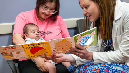 A Crusader Community Health provider shares a board book with a mother and her infant during a well-child visit as part of the Reach Out & Read program.